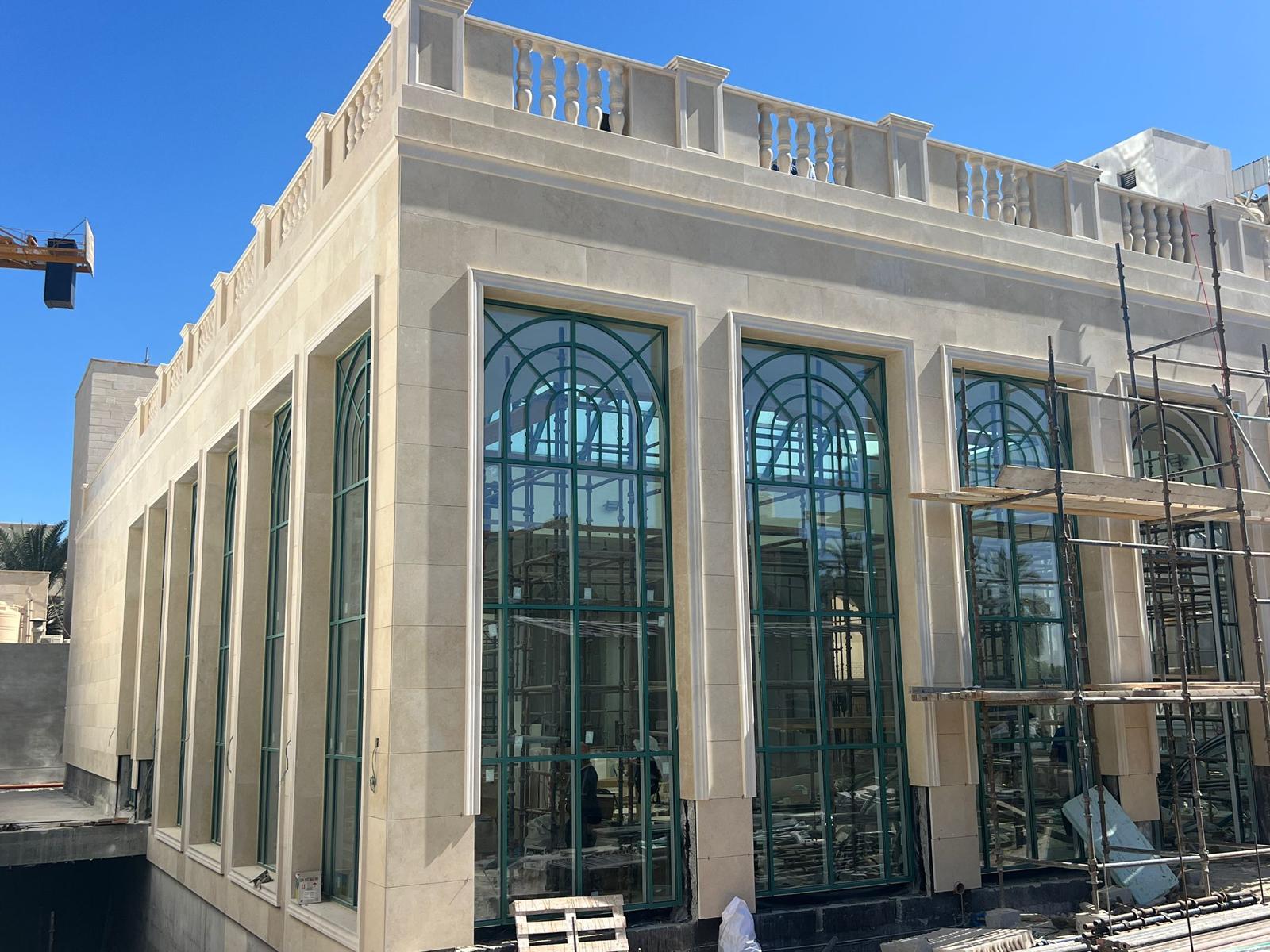 Stone villa facade with arched green-framed windows built by CEMENTO